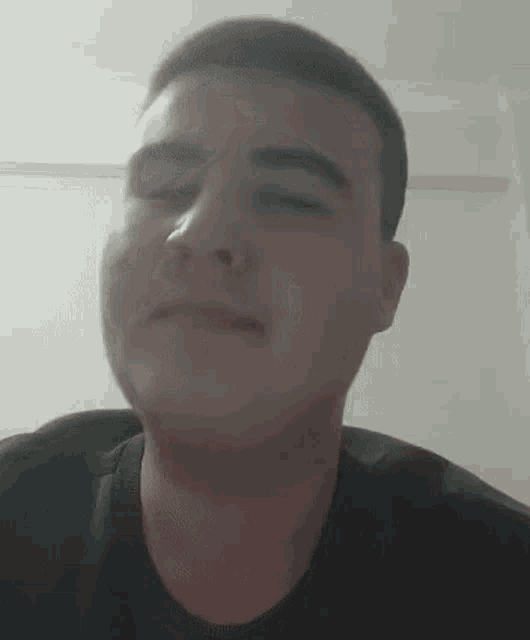 a young man is making a funny face with his eyes closed .
