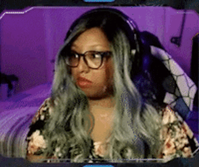 a woman wearing glasses and headphones is sitting in front of a computer monitor .
