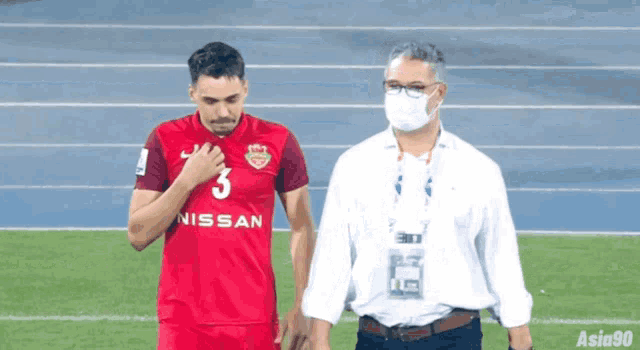 a man wearing a mask stands next to a nissan soccer player
