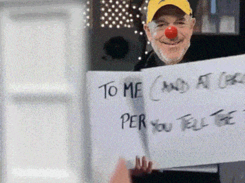a man with a red nose is holding up a sign that says to me and at christmas per you tell the