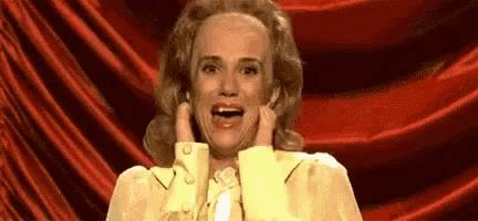 a woman in a yellow dress is making a funny face with her hands on her face .
