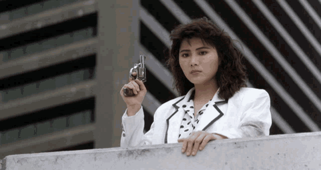 a woman in a white jacket holds a gun in her right hand