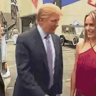 a man in a suit and tie is standing next to a woman in a red top .