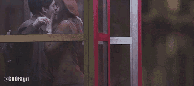 a man and woman kissing in front of a phone booth with cuorigif written on the bottom