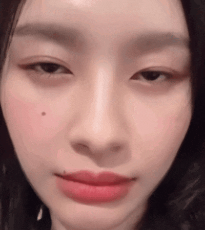 a close up of a woman 's face with a small spot on her cheek