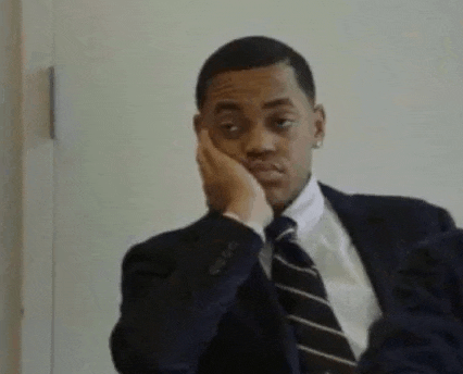 a man in a suit and tie is sitting down with his hand on his chin .
