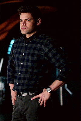 a man wearing a plaid shirt has his hands on his hips