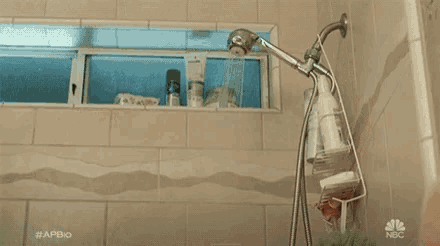 a shirtless man is taking a shower in a bathroom with a shower head .