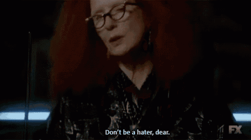 a woman with red hair and glasses is talking to someone .