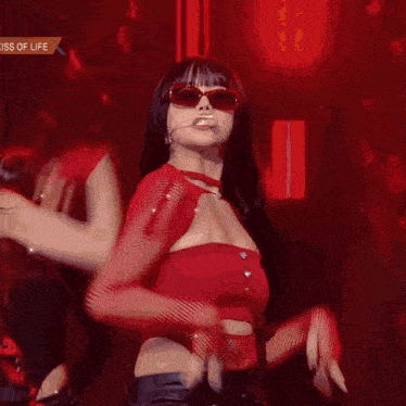 a woman wearing sunglasses and a red top is dancing on stage