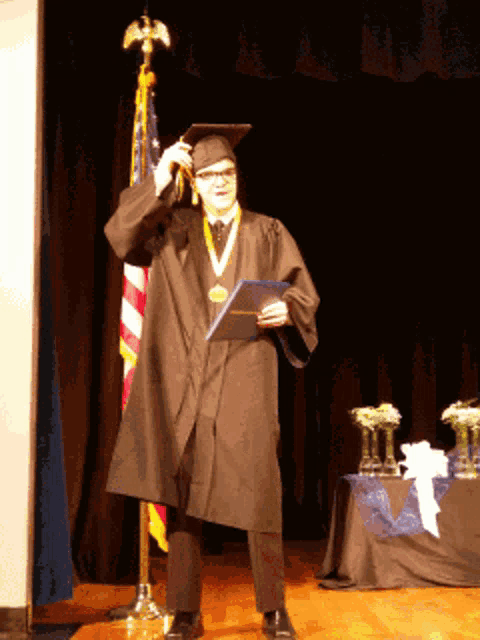 a man in a graduation cap and gown holds a certificate
