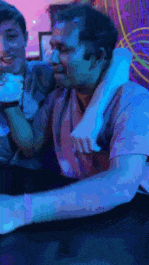a man is holding another man 's arm in a blue light