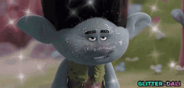 a troll with a lot of glitter on his face is looking at the camera .