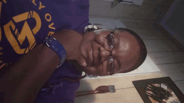a woman wearing glasses and a purple shirt that says " love "