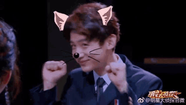 a man in a suit and tie is making a cat face with his fist .