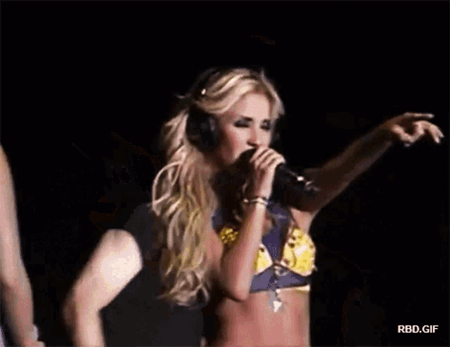 a woman wearing headphones is singing into a microphone on a stage