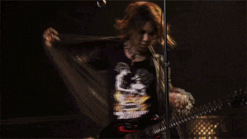a man is playing a guitar and singing into a microphone in a dark room
