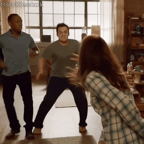 a woman in a plaid shirt is standing in front of two men in a living room