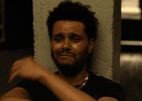 a man with a beard is crying while leaning against a concrete wall