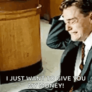 a man in a suit and tie is sitting on the floor talking on a cell phone and holding his head .