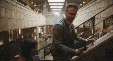 a man in a suit and glasses is standing on a set of stairs next to a woman .
