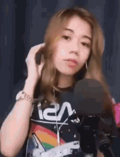 a woman is talking on a cell phone in front of a microphone while wearing headphones .
