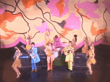 a group of people playing instruments on a stage with a colorful background