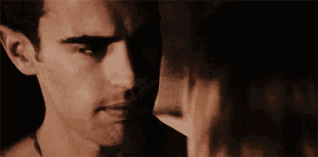 a close up of a man and woman kissing with a dark background