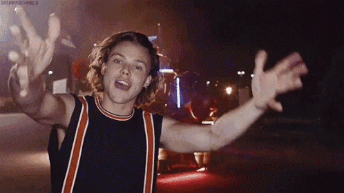 a young man is standing in front of a microphone with his arms outstretched in the air .