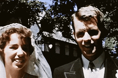 a bride and groom are posing for a picture on their wedding day and smiling .