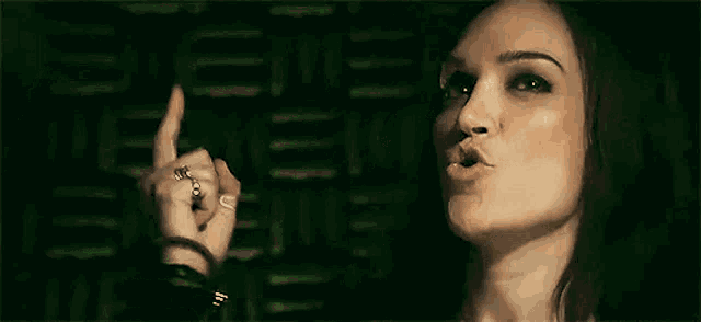 a woman is blowing a kiss while pointing her finger at something .