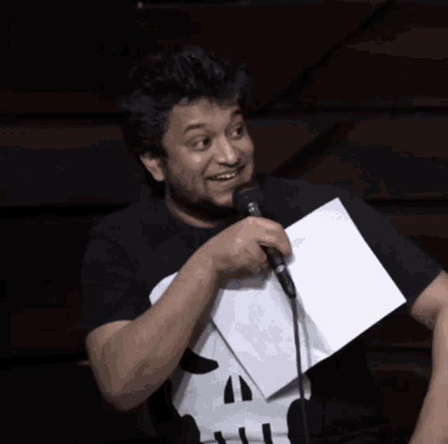 a man holding a piece of paper and a microphone