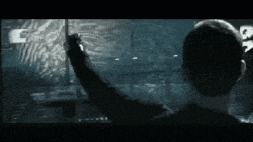 a man is standing in front of a computer screen and pointing at something .