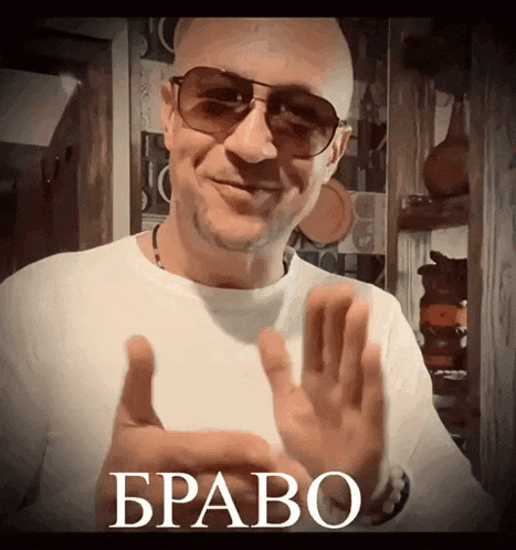 a man wearing sunglasses and a white shirt with the word bravo on the bottom