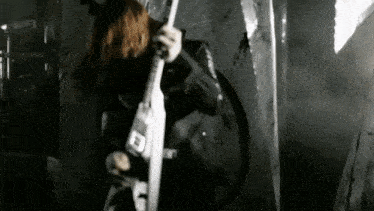 a black and white photo of a man playing a guitar in a dark room .