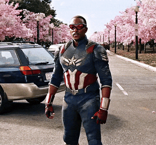a man in a captain america costume is standing in front of a blue suv