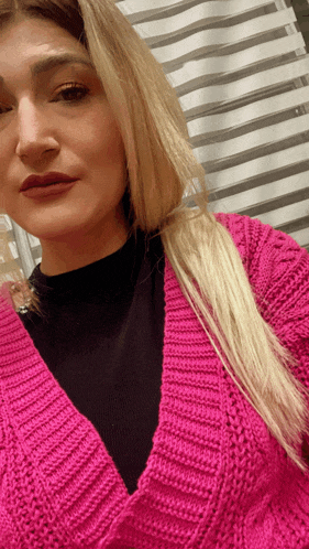 a woman is wearing a pink sweater and black top
