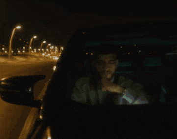 a man is talking on a cell phone while driving a car at night