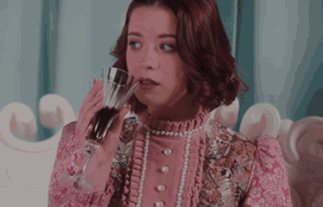 a woman in a pink dress is holding a glass of wine