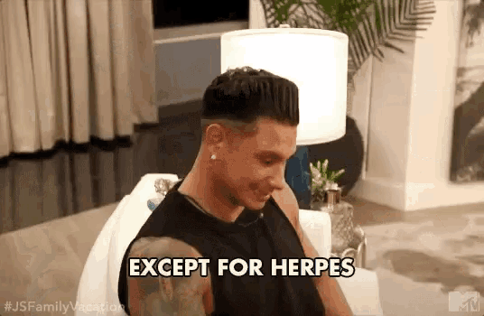 a man is sitting on a couch in a living room and says except for herpes .