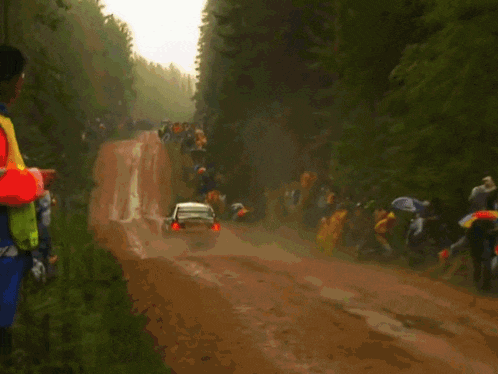 a blue subaru rally car driving down a dirt road