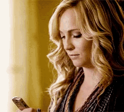 a woman with blonde hair is looking at her cell phone