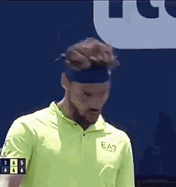 a man wearing a headband and a yellow shirt that says ea7