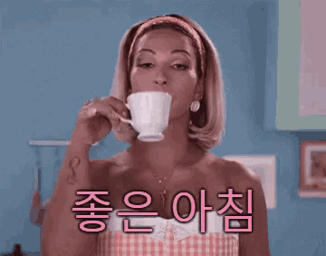 a woman is drinking a cup of coffee in a kitchen with korean writing on the bottom