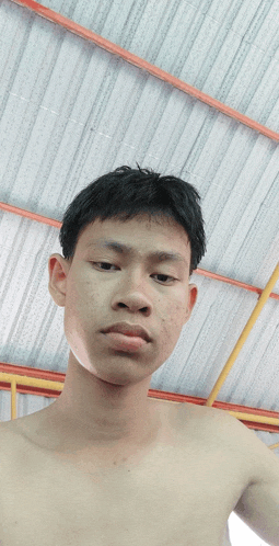a shirtless young man taking a picture of himself