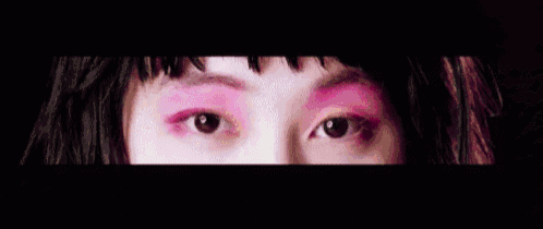 a close up of a woman 's face surrounded by pink powder .
