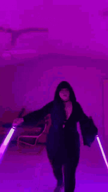 a woman is dancing in front of a purple light