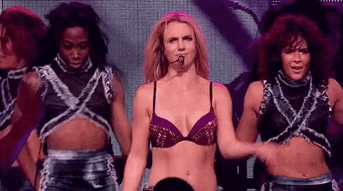 a woman in a bra is standing on a stage with a microphone in her hand .