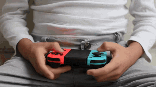 a person holding a nintendo switch controller in their hands