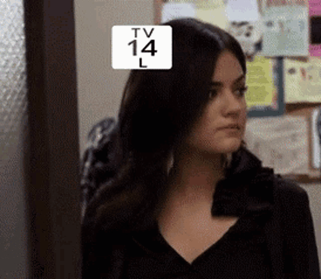 a woman is standing in front of a bulletin board with tv 14 l on it